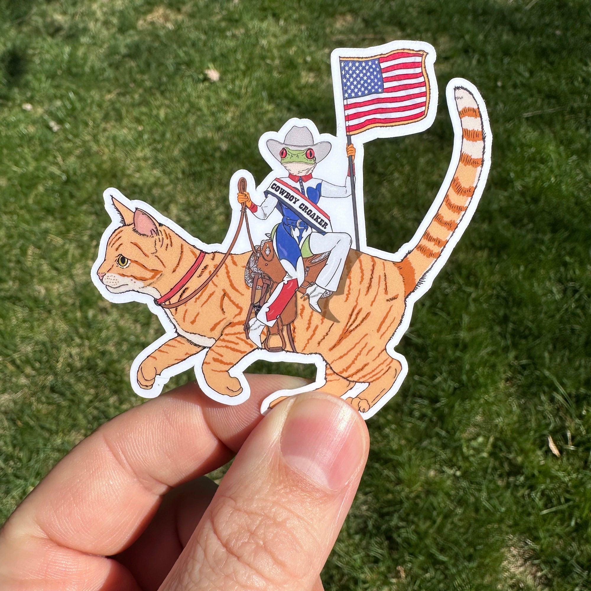Sticker of A frog wearing cowboy gear riding a cat like a horse, parodying Beyoncé's Cowboy Carter album
