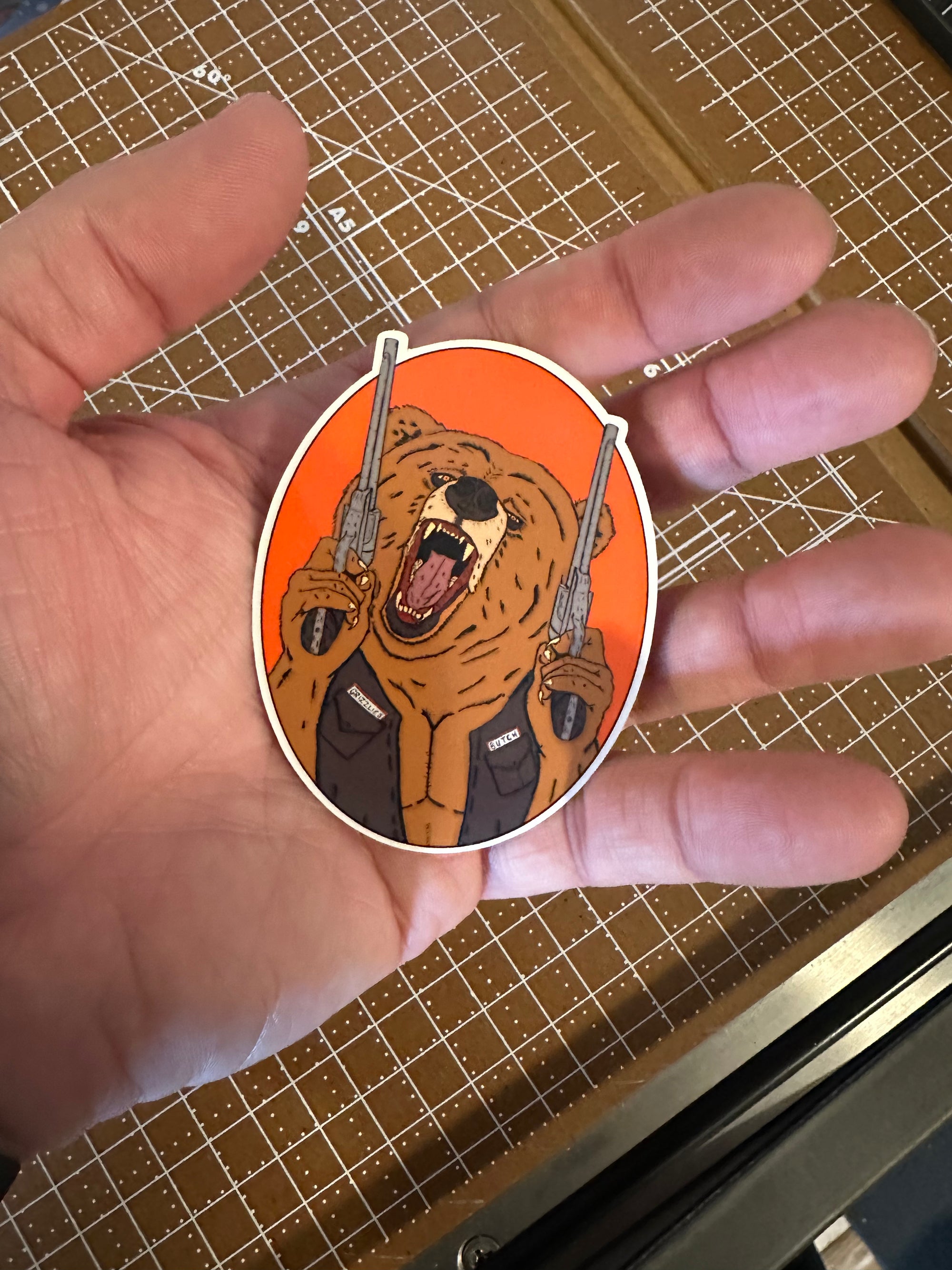 Sticker of A roaring grizzly bear wearing a leather jacket and holding two smoking pistols